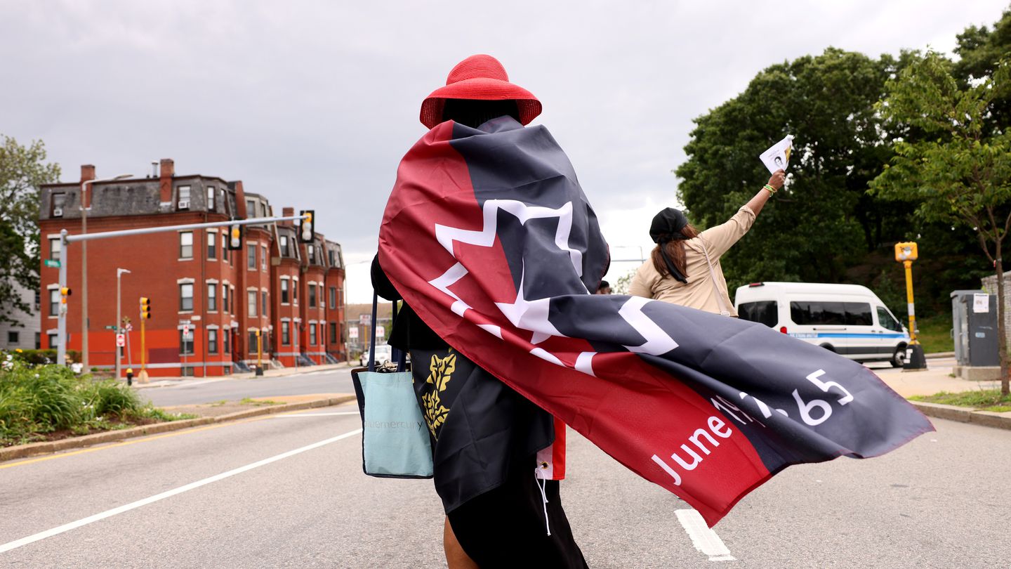 Kin Southern Table + Bar in Providence, R.I., kicks off Juneteenth Weekend with the 3rd Annual Juneteenth Block Party on June 16. Above, Antonia Edwards of New Haven wrapped herself in a Juneteenth flag and a Black heritage flag as she took part in a Juneteenth Emancipation Observance parade.